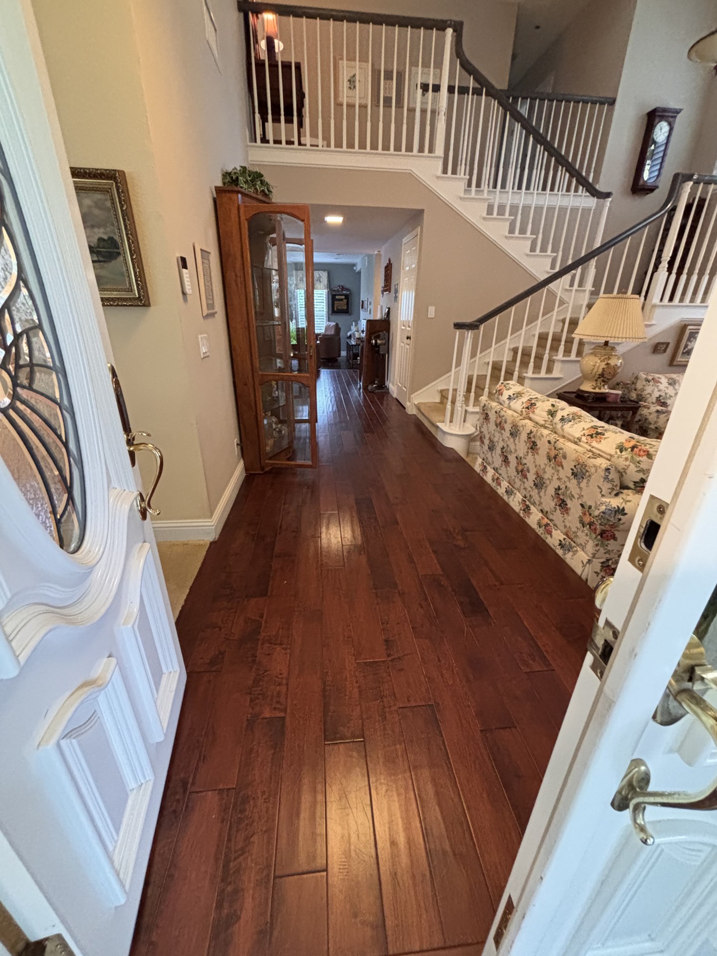 Dark wood-look entryway flooring beside an ornate staircase